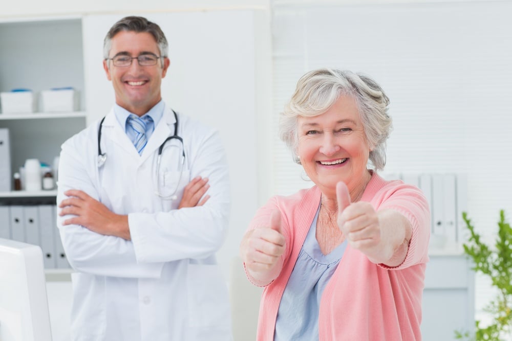 Portrait of happy female patient showing thumbs up sign while standing with doctor in clinic-1.jpeg